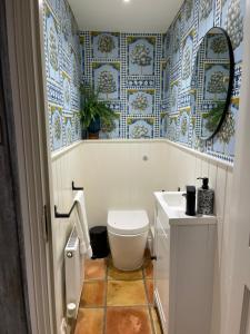 a bathroom with a toilet and blue and white tiles at No33 WOODLANDS BOUTIQUE COTTAGE in Heacham +18 photos