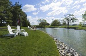 two white chairs sitting on the grass next to a river at Fulton Steamboat Inn in Lancaster