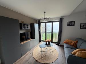 a living room with a couch and a table at Les Murmures du Rhône - Appartement Cosy et Lumineux in Andance