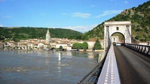 a bridge over a river with a town in the background at Les Murmures du Rhône - Appartement Cosy et Lumineux in Andance