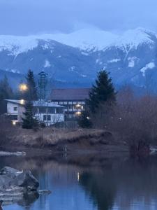 a building next to a river with mountains in the background at Serenity Colibița in Colibiţa