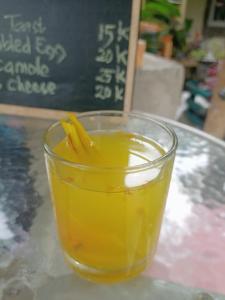 a glass of orange juice sitting on a table at JE House in Ambarita
