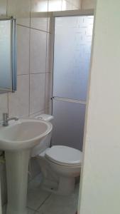 a bathroom with a white toilet and a sink at Suite Recanto Cheiro Verde in Caraguatatuba