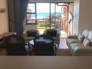 a living room with a couch and chairs and a balcony at King Fisher 6 in Mossel Bay