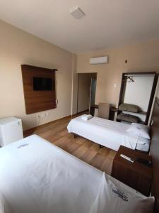 a hotel room with two beds and a mirror at Hotel Colibri Viçosa - Próximo a UFV in Viçosa