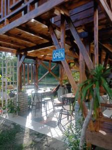 a patio with tables and chairs and a sign that reads open at JE House in Ambarita