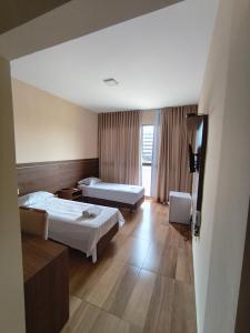 a hotel room with two beds and a television at Hotel Colibri Viçosa - Próximo a UFV in Viçosa