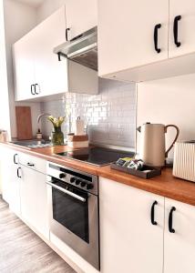 a kitchen with white cabinets and a stove top oven at Haus Gitta - Wohlfühlen & Genießen in Luckenwalde