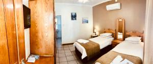 a hotel room with two beds and a mirror at Loskop Valley Lodge in Groblersdal +28 photos