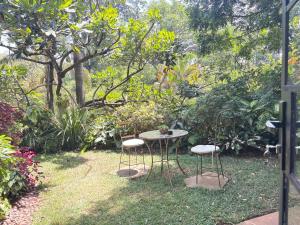 a table and two chairs in a garden at Hornbill Cottage in Nairobi