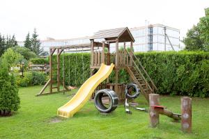 a wooden playground with a slide in the grass at Mamos virtuve in Avižieniai