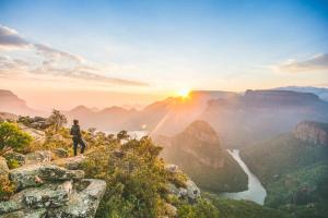 a man standing on the edge of a mountain overlooking a canyon at Round Here Self-Catering Holiday Home in Sabie +28 photos