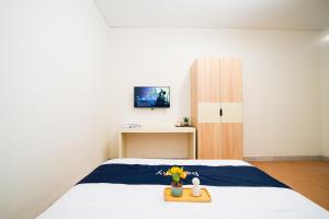 a bedroom with a bed and a table with flowers on it at Behomy Urban Point Karawang in Karawang