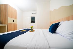 a large white bed with a vase of flowers on it at Behomy Urban Point Karawang in Karawang
