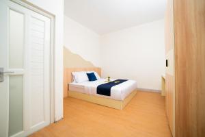 a bedroom with a bed in a white room at Behomy Urban Point Karawang in Karawang