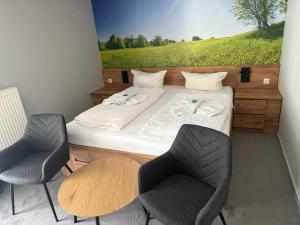 a bedroom with two beds with chairs and a painting on the wall at Natur& Waldhotel Johannesruh in Wesenberg