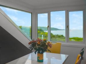 a vase with flowers on a table in front of windows at Headlands Hideaway in Coverack