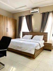 a bedroom with a large bed and a chair at Lux-Home Enugu in Enugu