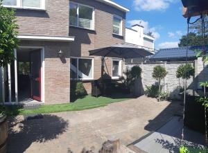 a patio with an umbrella in front of a house at Thuis op Flakkee in Ooltgensplaat
