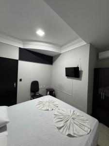 a bedroom with a white bed and a television at Hotel Samaritano in Montes Claros