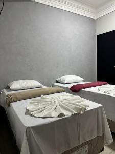 two beds in a room with white walls at Hotel Samaritano in Montes Claros