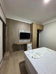a bedroom with a bed and a flat screen tv at Hotel Samaritano in Montes Claros +40 photos