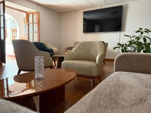 a waiting room with chairs and a table and a tv at Posada Del Corregidor in Cajamarca