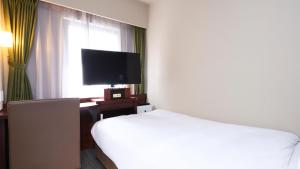 a hotel room with a bed and a flat screen tv at Dormy Inn Himeji Natural Hot Spring in Himeji
