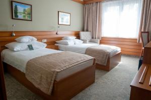 a hotel room with two beds and a window at Hotel Club Tisza in Lakitelek +33 photos