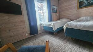 a bedroom with two beds and a tv and a window at Boutique Hotelli Kivennapa in Pieksä