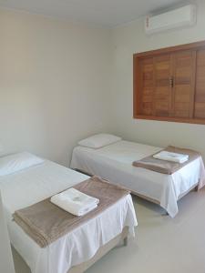 a room with two beds and a cabinet with towels at Pousada Jubarte in Serra