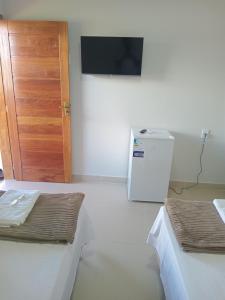 a room with two beds and a door and a refrigerator at Pousada Jubarte in Serra