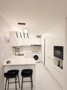 a kitchen with white cabinets and black stools at 해변1분 숙소 광안이즘, 1 min to beach Gwangan-ism in Kwangan-dong
