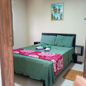 a bedroom with a bed with a green comforter at Paim`s Village Itacaré in Itacaré