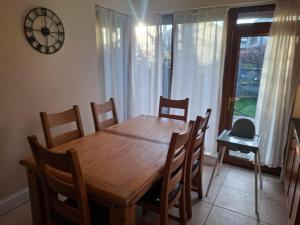 a dining room table with chairs and a clock on the wall at Rostrevor Beach House in Rostrevor