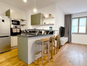 a kitchen with a counter and some stools in it at TrulySpace - Modernes Apartment am Rathausplatz, Terrasse, Fahrstuhl in Augsburg