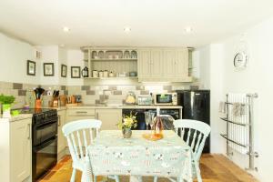 a kitchen with a table with four chairs and a kitchen with white cabinets at Mill Cottage, Hanley Mill in Tenbury