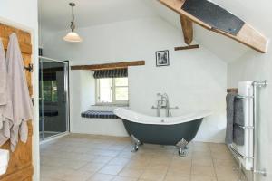a bathroom with a bath tub and a sink at Mill Cottage, Hanley Mill in Tenbury