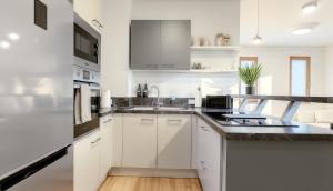 a kitchen with white cabinets and black counter tops at TrulySpace - Modernes Apartment am Rathausplatz, Terrasse, Fahrstuhl in Augsburg +5 photos