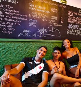 a group of three people sitting in front of a menu at Cocos Hostel Rio in Rio de Janeiro