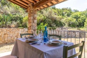 a table with plates and glasses and a bottle at Apartments La Tenuta where the sea meets the land - Goelba in Porto Azzurro