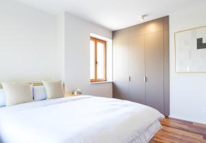 a bedroom with a large white bed and a window at TrulySpace - Modernes Apartment am Rathausplatz, Terrasse, Fahrstuhl in Augsburg