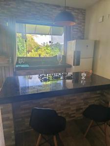 a kitchen with a counter with two chairs and a window at Espaço Bahia Bella in Porto Seguro +8 photos