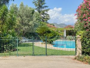 a green fence with a swimming pool behind it at Gite Mireille in Carros