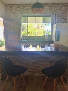 a kitchen with a counter and two bar stools at Espaço Bahia Bella in Porto Seguro