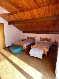 two beds in a room with a wooden ceiling at Chalet les Lurins in Villarlurin