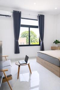 a bedroom with a bed and a laptop on a table at The One Apartments in Tân Uyên