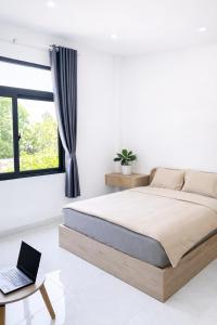 a bedroom with a bed and a laptop on a table at The One Apartments in Tân Uyên