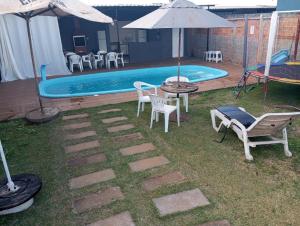 a pool with a table and chairs and an umbrella at QUARTO CONTEINER, EDICULA ABERTA E PISCINA AQUAVibes in Cascavel
