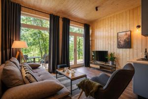 a living room with a couch and a tv at Apartamenty Leśna Przystań nad jeziorem in Węgorzewo